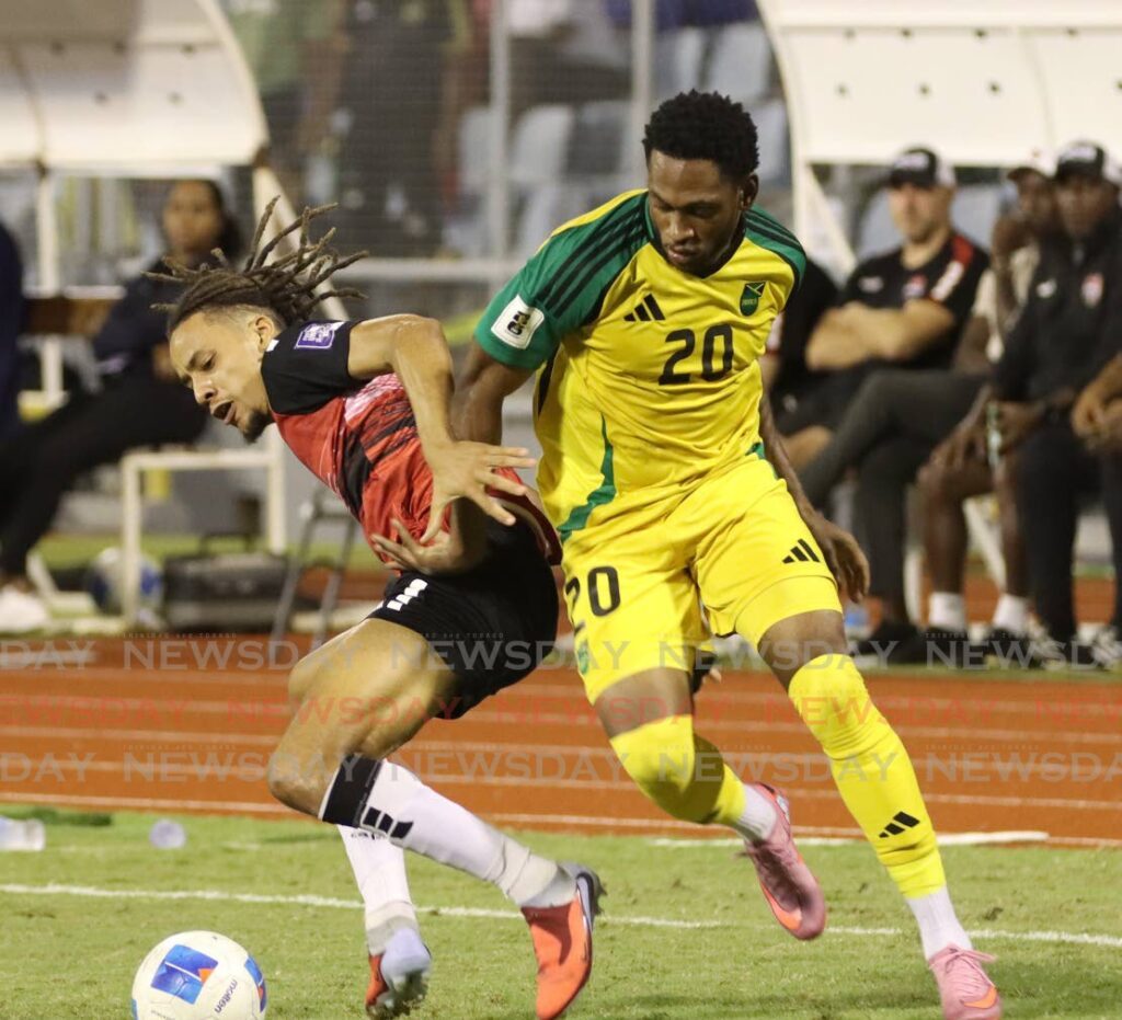 TT’s defender Deron Payne (L) screens the ball from Renaldo Cephas of Jamaica, in their World Cup qualifier match, at the Hasley Crawford Stadium on November 13. - Photo by Angelo Marcelle (Image obtained at newsday.co.tt)